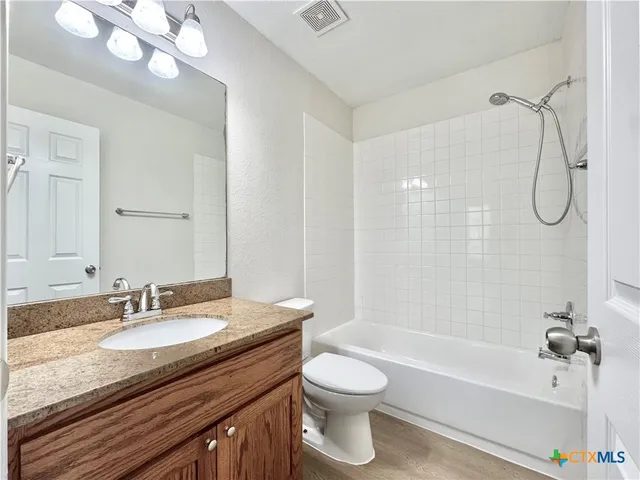 a bathroom with a granite countertop sink a toilet a mirror a bathtub and shower
