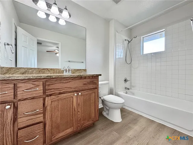 a bathroom with a granite countertop toilet a sink a mirror a bathtub and shower