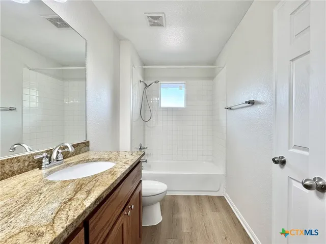 a bathroom with a granite countertop sink a toilet and shower