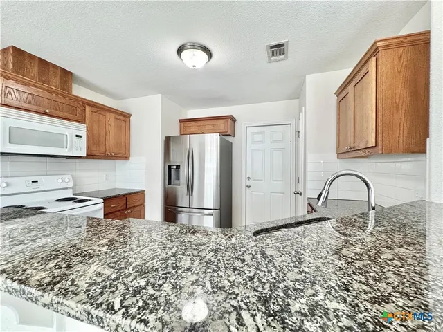 a kitchen with stainless steel appliances kitchen island granite countertop a refrigerator and a stove top oven