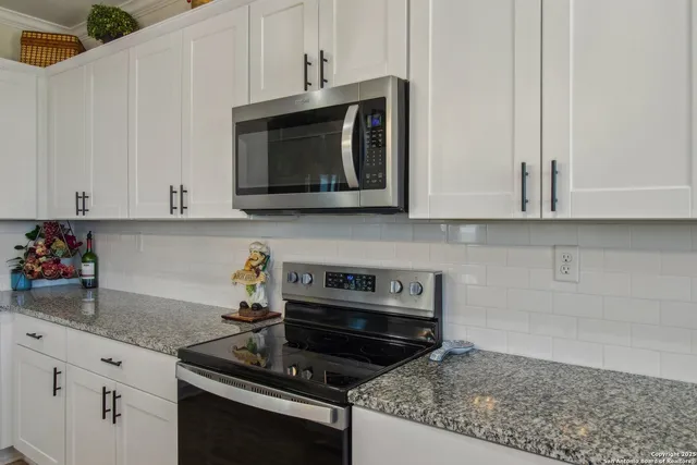 a kitchen with granite countertop white cabinets stainless steel appliances and sink