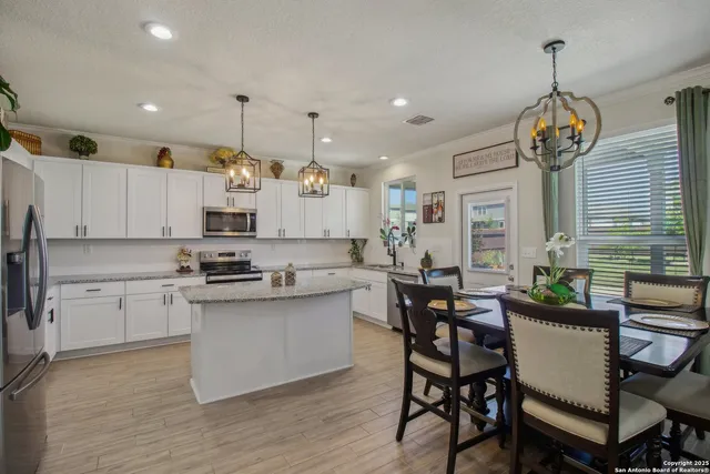 a kitchen with stainless steel appliances kitchen island granite countertop a table chairs and a stove