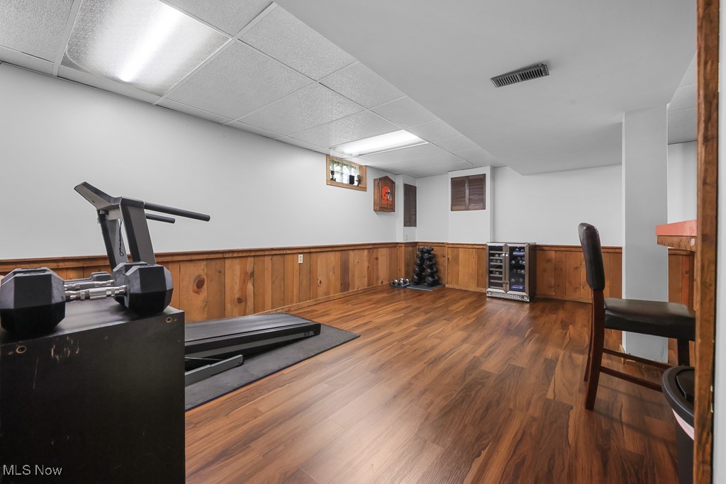547 Lansing Road Akron, OH 44312 - Photo 33 of 50 Workout area with wooden walls, dark wood-style floors, a drop ceiling, wine cooler, and wainscoting