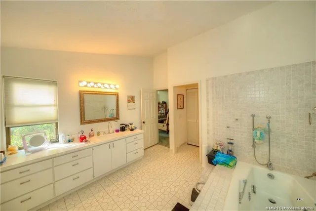 a spacious bathroom with a double vanity sink mirror and bathtub