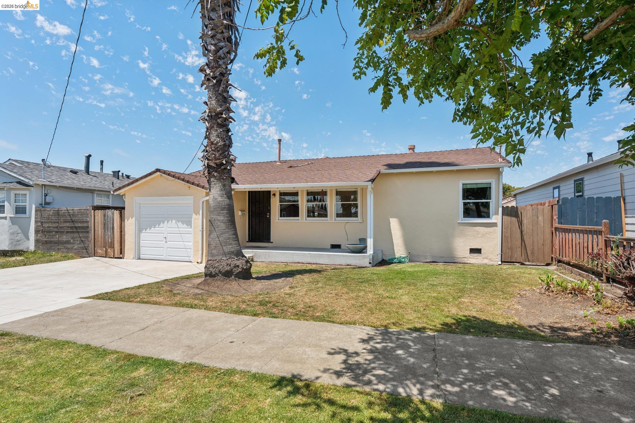 Single-story residence featuring a light-colored stucco exterior, attached garage, and a concrete driveway