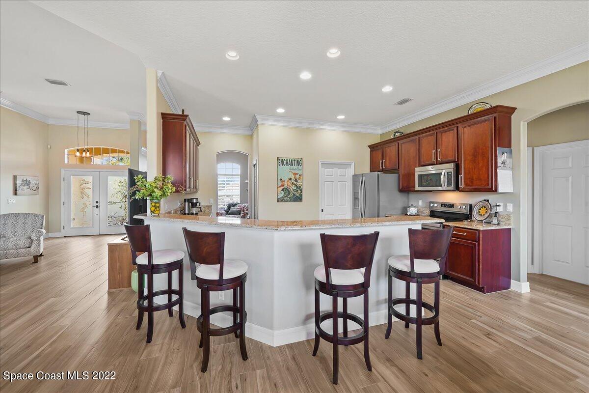 245 Clyde Street Melbourne Beach, FL 32951 - Photo 11 of 47 a kitchen with stainless steel appliances granite countertop wooden floor dining table and chairs