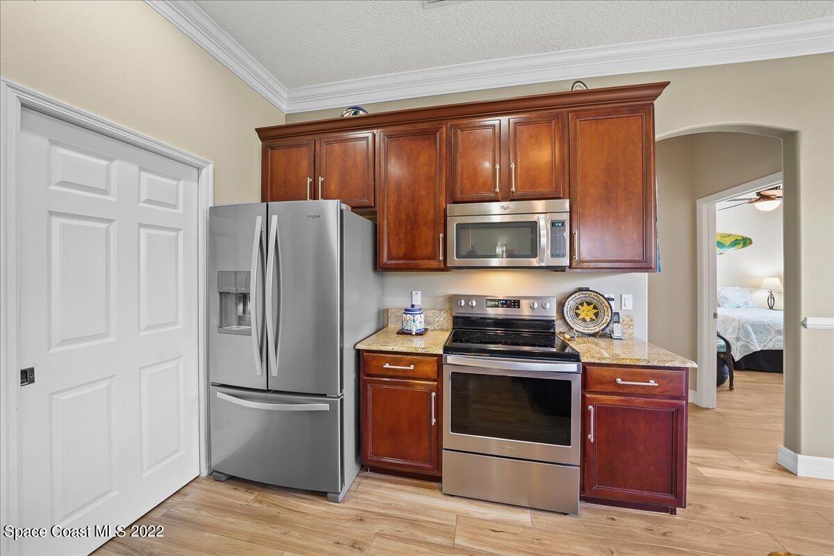 245 Clyde Street Melbourne Beach, FL 32951 - Photo 13 of 47 a kitchen with wooden cabinets and stainless steel appliances