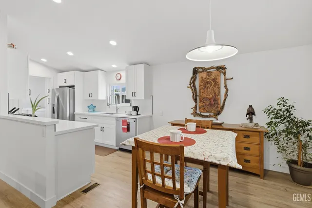 a open dining room with kitchen island a wooden floor and chairs