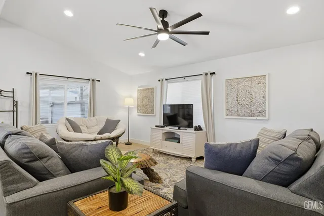 a living room with furniture a ceiling fan a flat screen tv and a window