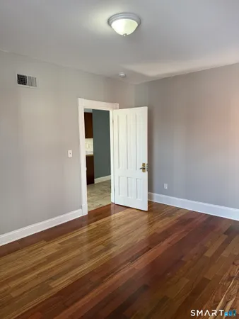 a view of an empty room with wooden floor and closet