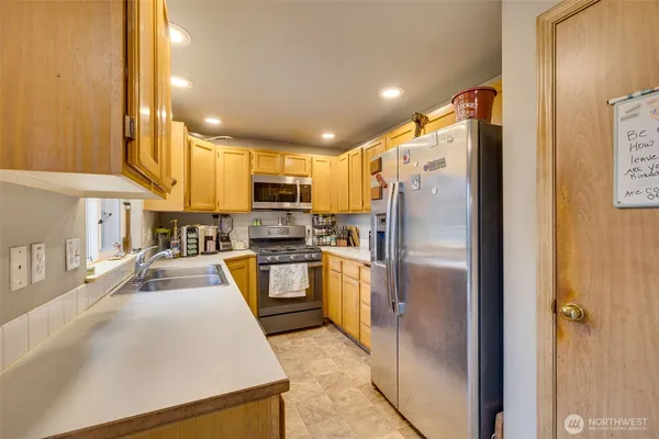 a kitchen with stainless steel appliances granite countertop a refrigerator a stove and a sink