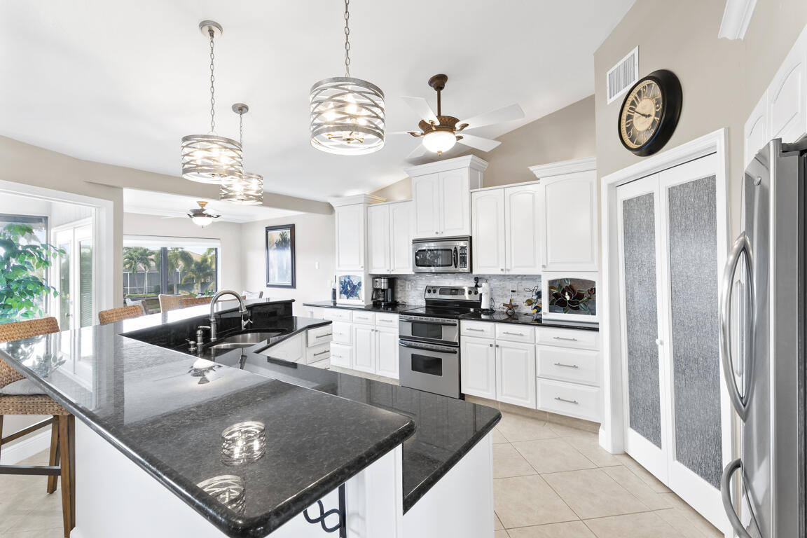 110 June Court Marco Island, FL 34145 - Photo 8 of 41 a kitchen with stainless steel appliances granite countertop a stove a refrigerator a oven a sink a dining table and chairs with wooden floor