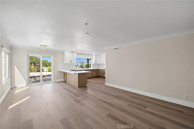 a living room with furniture and a kitchen area with wooden floor