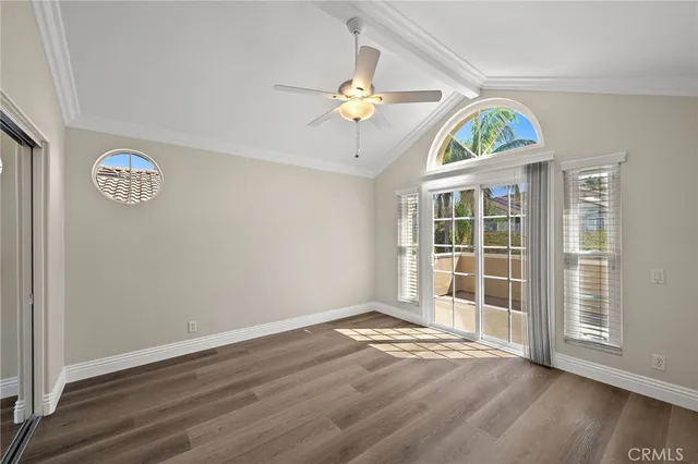 an empty room with wooden floor chandelier fan and windows