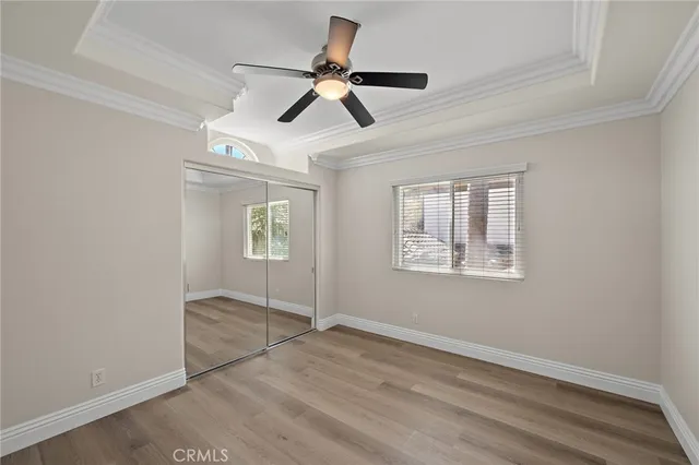 a view of empty room with wooden floor and ceiling fan