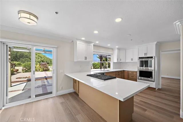 a kitchen with stainless steel appliances granite countertop a sink a stove and a wooden floors