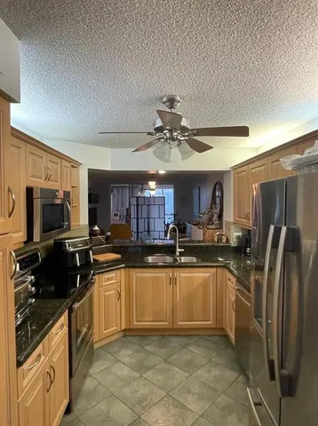 a kitchen with stainless steel appliances granite countertop a sink stove refrigerator and cabinets
