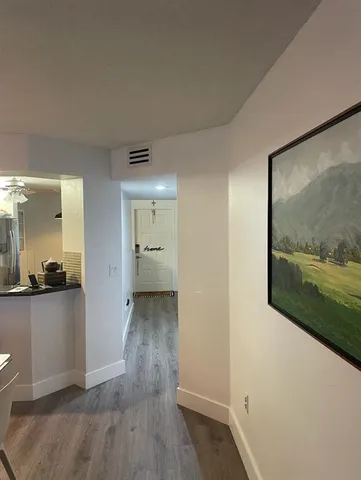 a view of a hallway with wooden floor and a bathroom