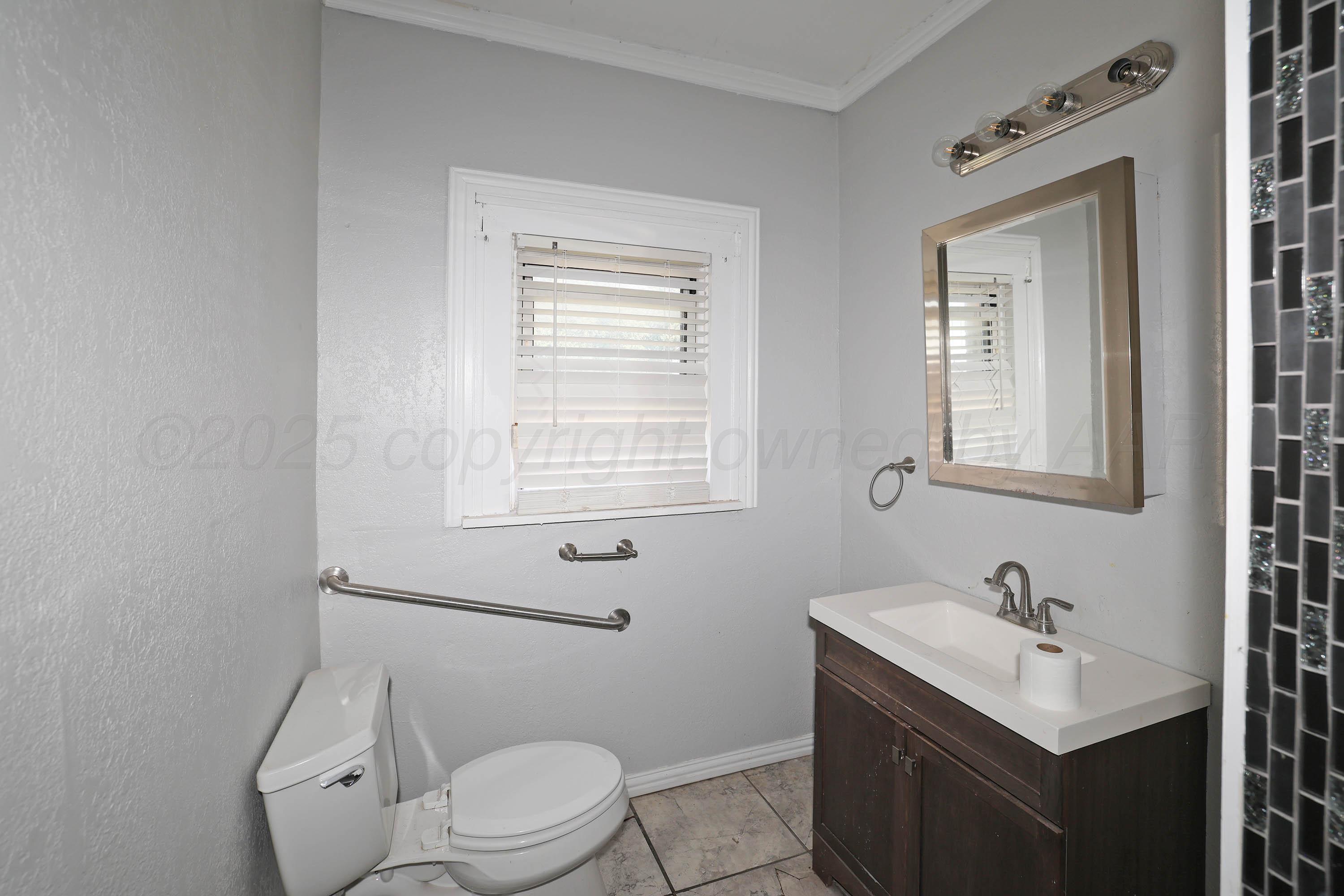 2001 Northwest 13th Avenue Amarillo, TX 79107 - Photo 25 of 35 a bathroom with a toilet a sink a mirror and a window