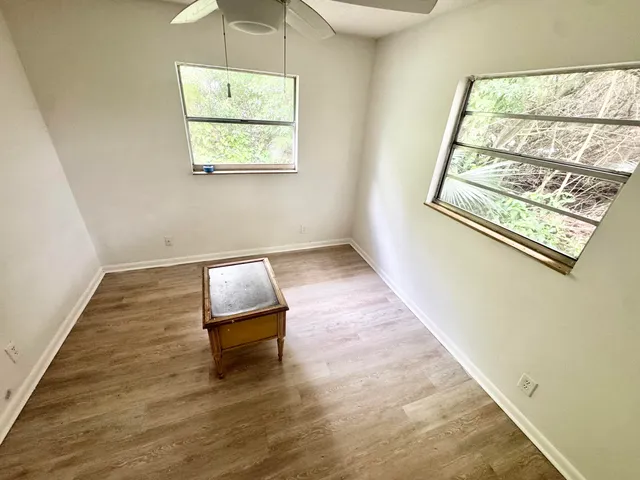 an empty room with wooden floor and windows