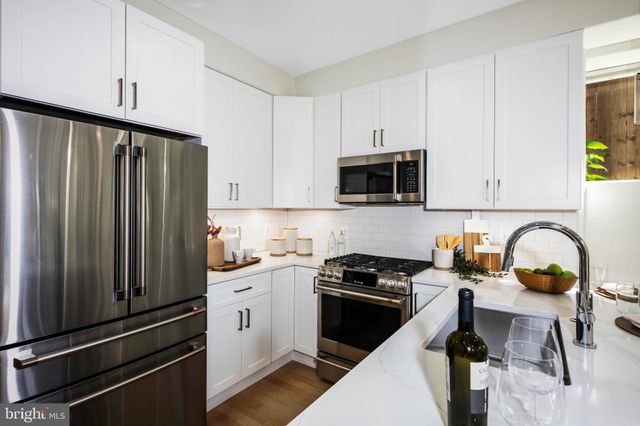 a kitchen with granite countertop a sink a stove and a wooden floor