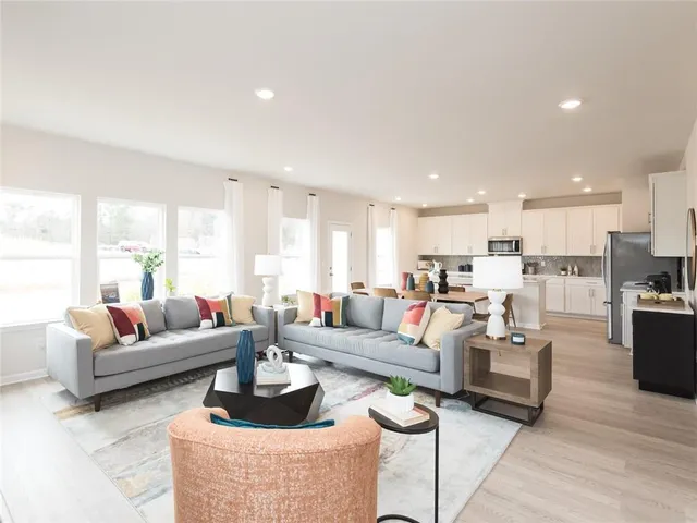 a living room with furniture kitchen view and a large window