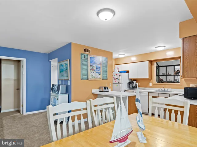 a living room with stainless steel appliances kitchen island granite countertop a table and chairs in it