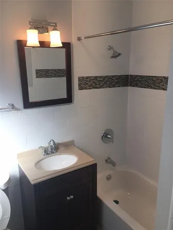 a bathroom with a sink and mirror with bathtub