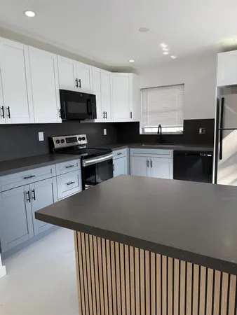 a kitchen with stainless steel appliances kitchen island granite countertop a sink dishwasher stove top oven and cabinets