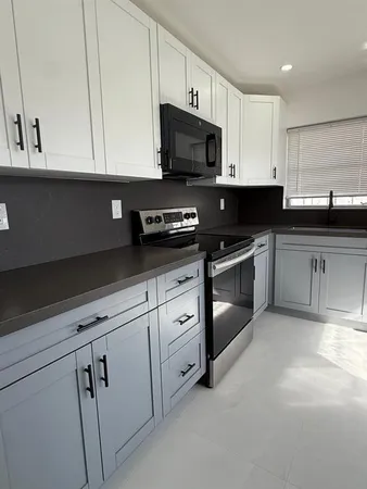 a kitchen with white cabinets and black appliances