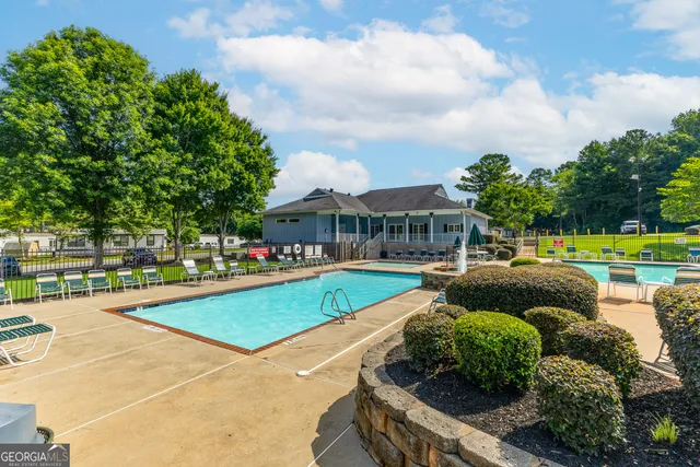 a view of a swimming pool with lawn chairs and plants
