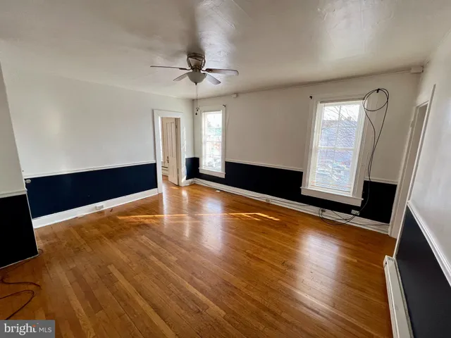 a view of an empty room with window and wooden floor