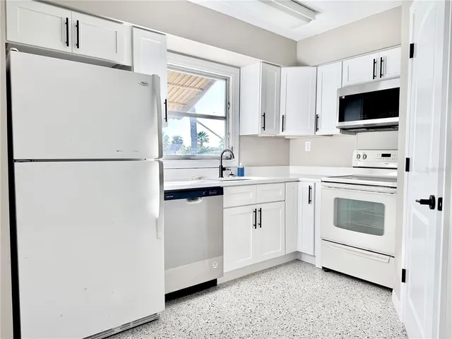 a kitchen with stainless steel appliances a refrigerator sink and white cabinets