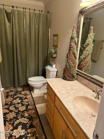 a bathroom with a granite countertop sink and a toilet