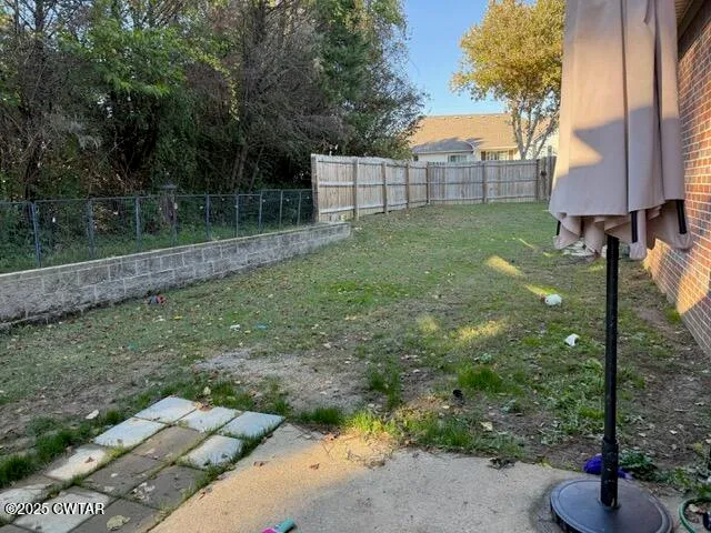 a view of a backyard with a large tree and wooden fence