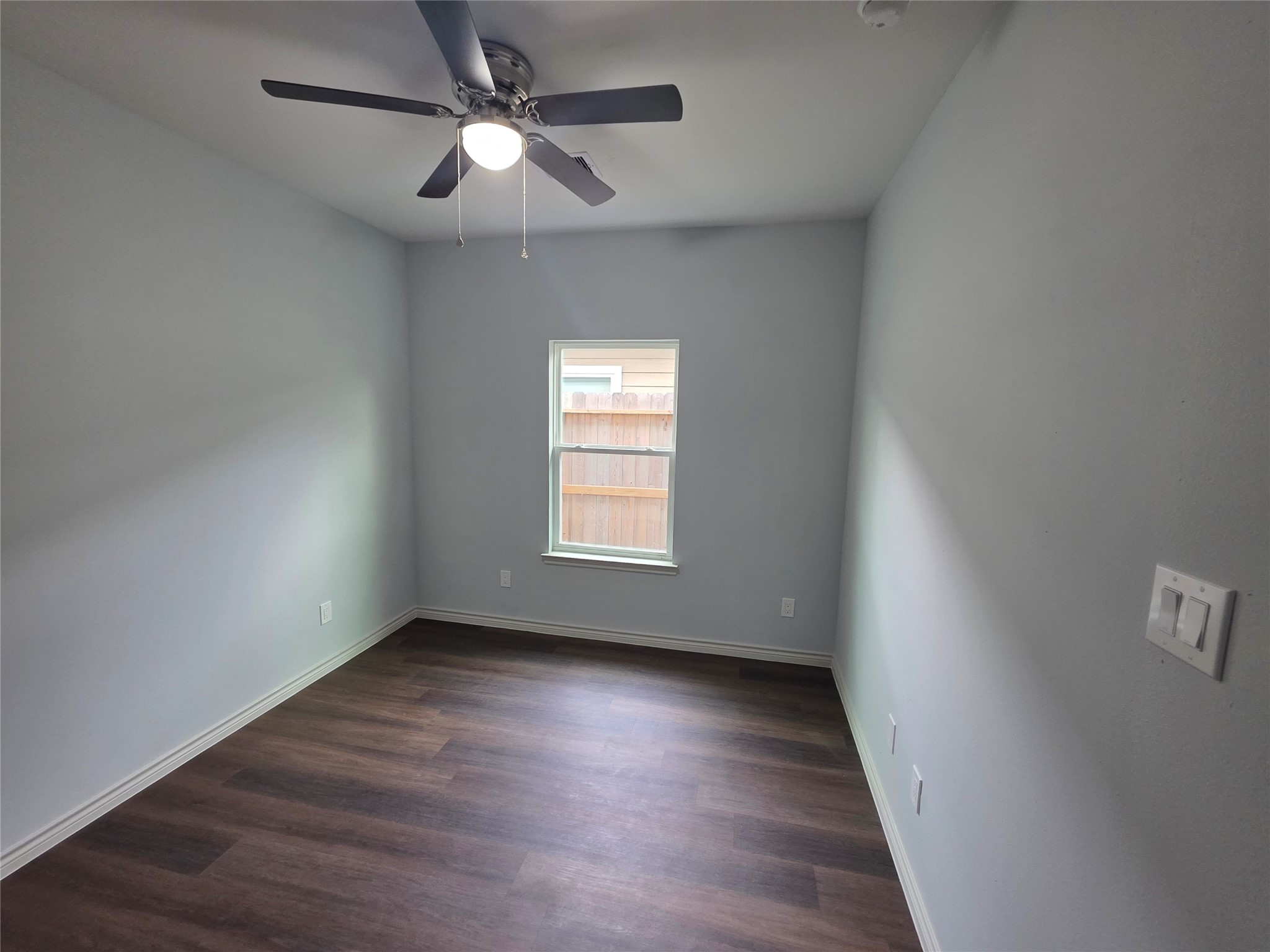 213 Dipping Stream Street Houston, TX 77076 - Photo 6 of 10 an empty room with wooden floor ceiling fan and windows