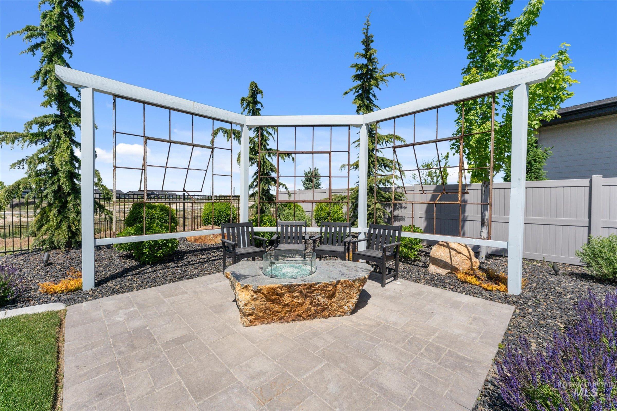 6585 South Pemberley Way Meridian, ID 83642 - Photo 42 of 43 Paver patio featuring a natural stone fire pit, surrounded by decorative white trellises