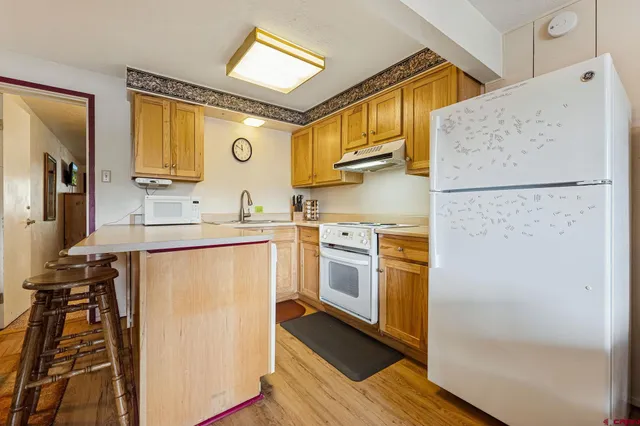 a kitchen with a refrigerator a sink and wooden floor
