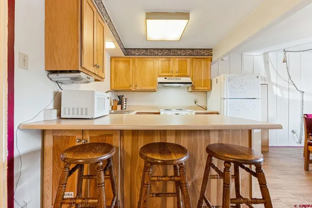 a kitchen with stainless steel appliances a table chairs in it and wooden floor
