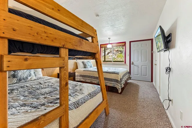 a bedroom with a bed and a flat tv screen on dresser