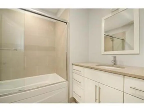 a bathroom with a granite countertop sink a mirror and a bathtub