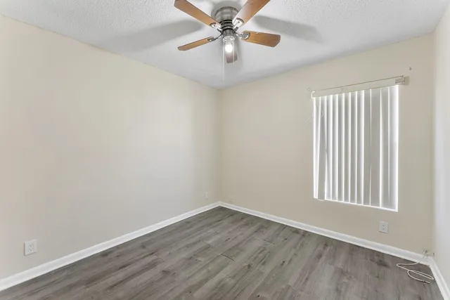 an empty room with a window and a ceiling fan