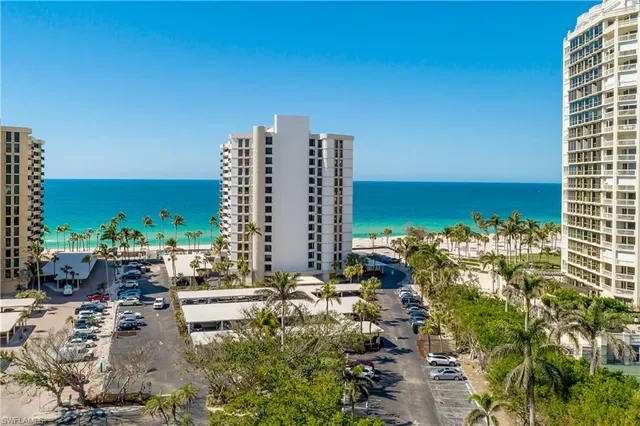 a view of ocean with a multi story building and trees in the background