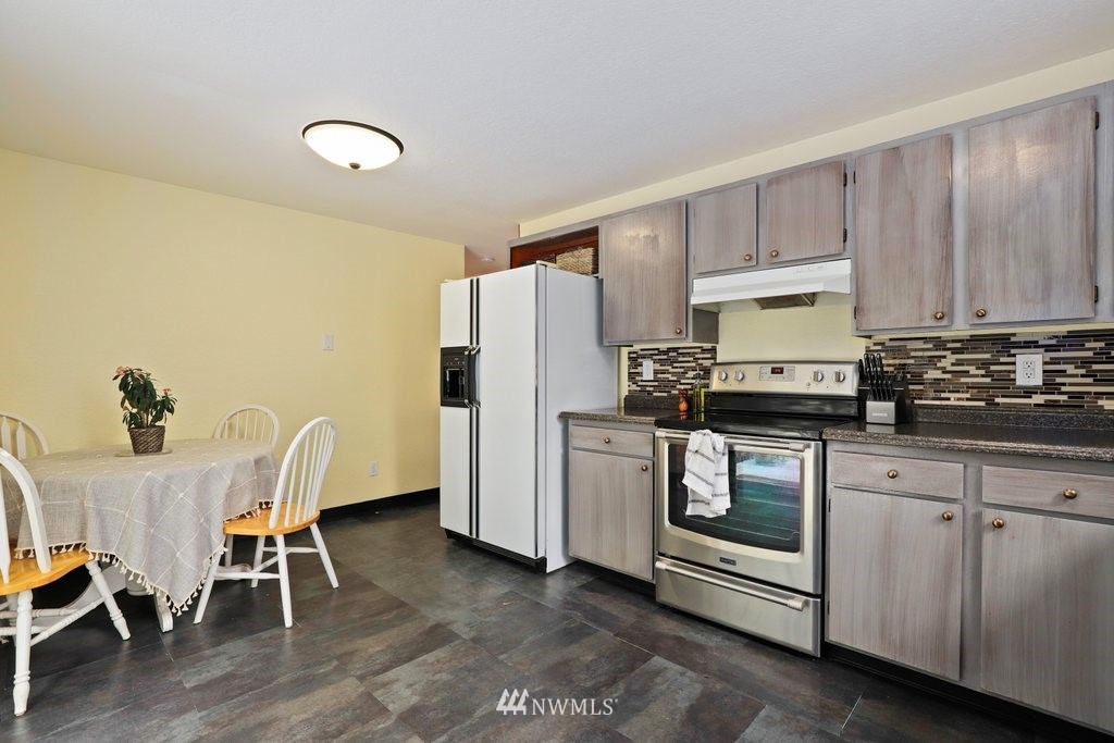 18216 19th Drive Southeast Bothell, WA 98012 - Photo 8 of 37 a kitchen with stainless steel appliances granite countertop a stove a sink a refrigerator a dining table and chairs