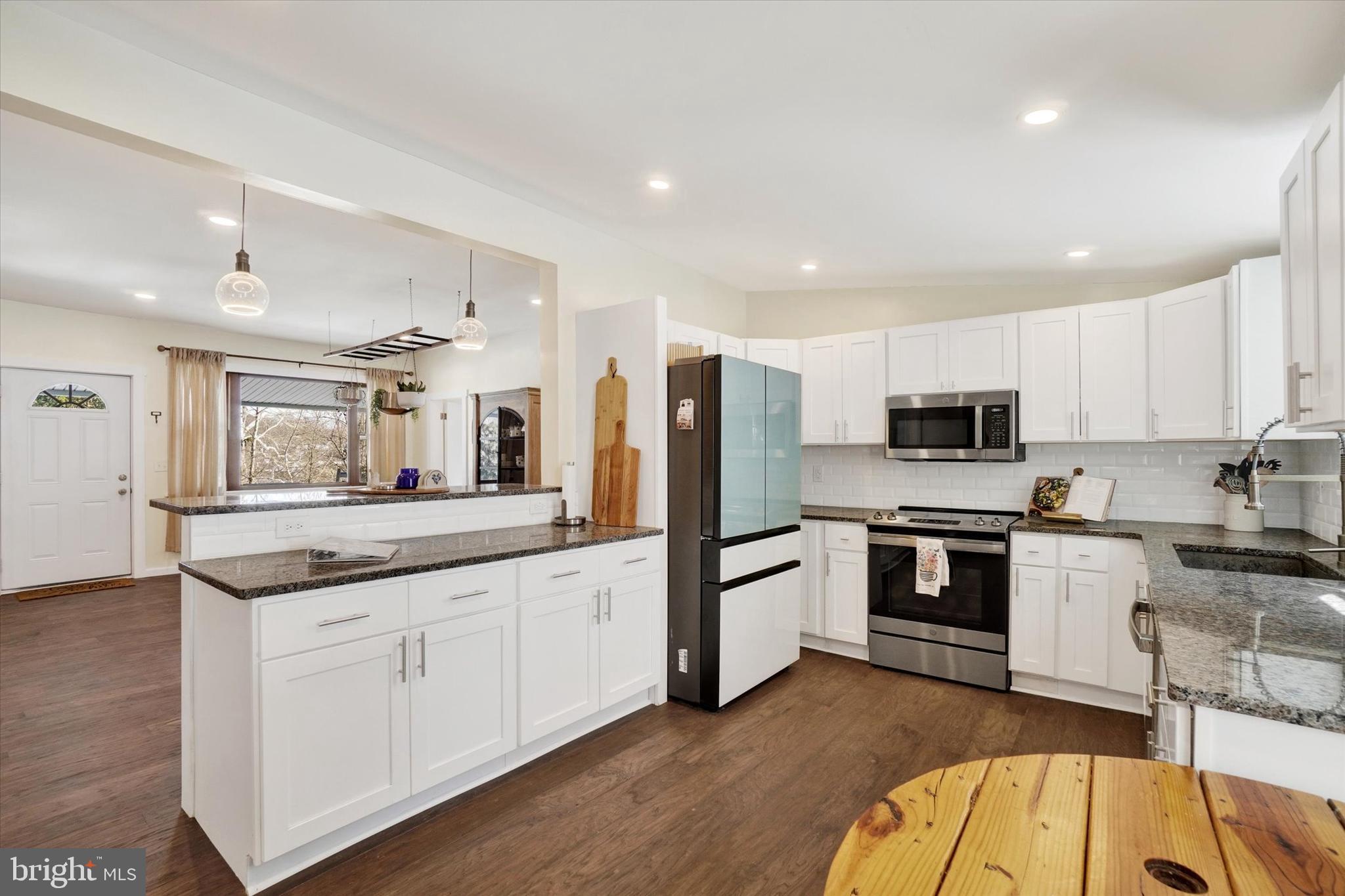 a kitchen with granite countertop white cabinets and stainless steel appliances