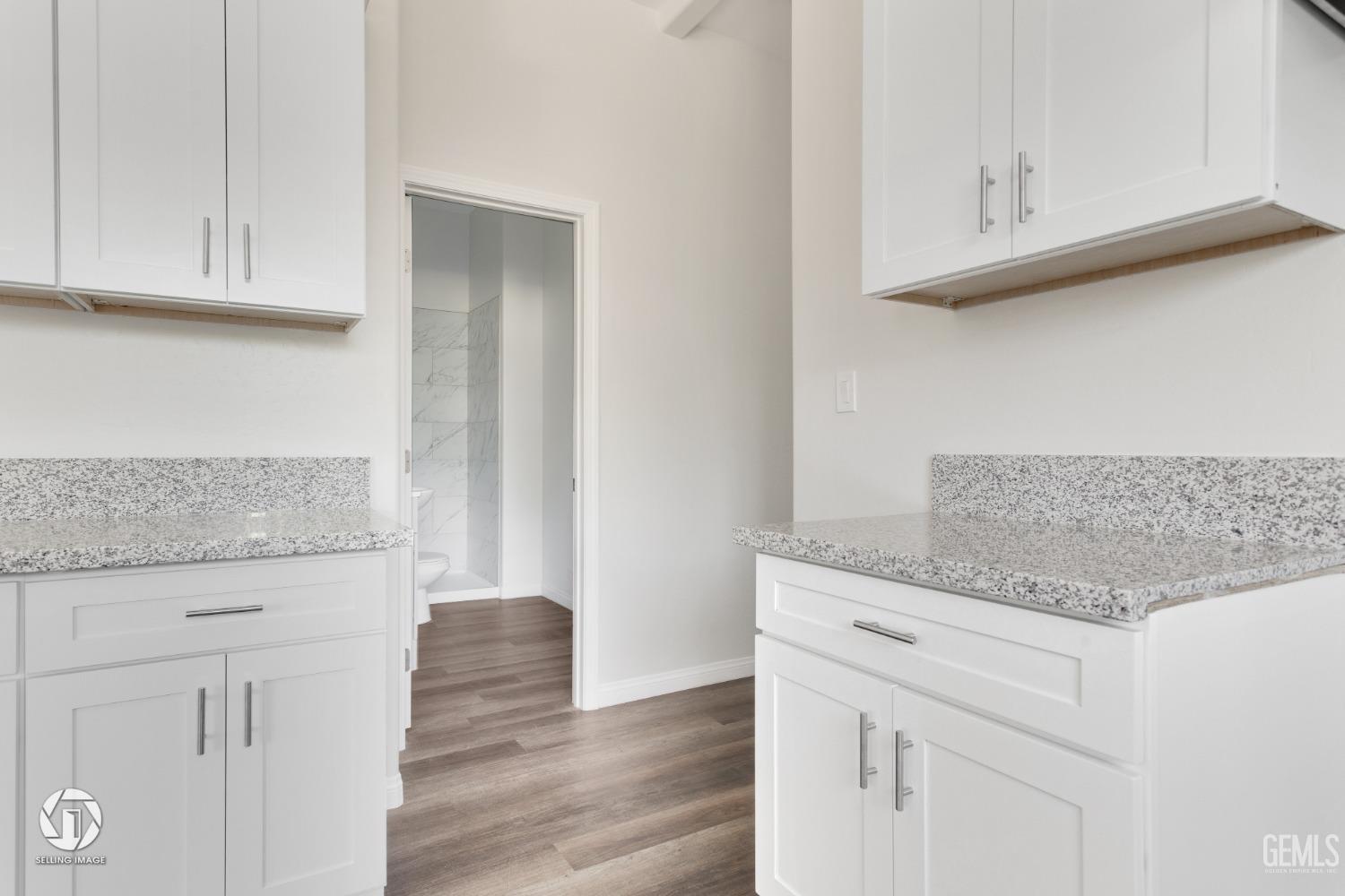 Undisclosed Address Bakersfield, CA 93305 - Photo 20 of 28 a kitchen with granite countertop white cabinets and a wooden floor