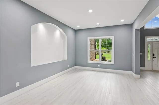 an empty room with wooden floor and windows