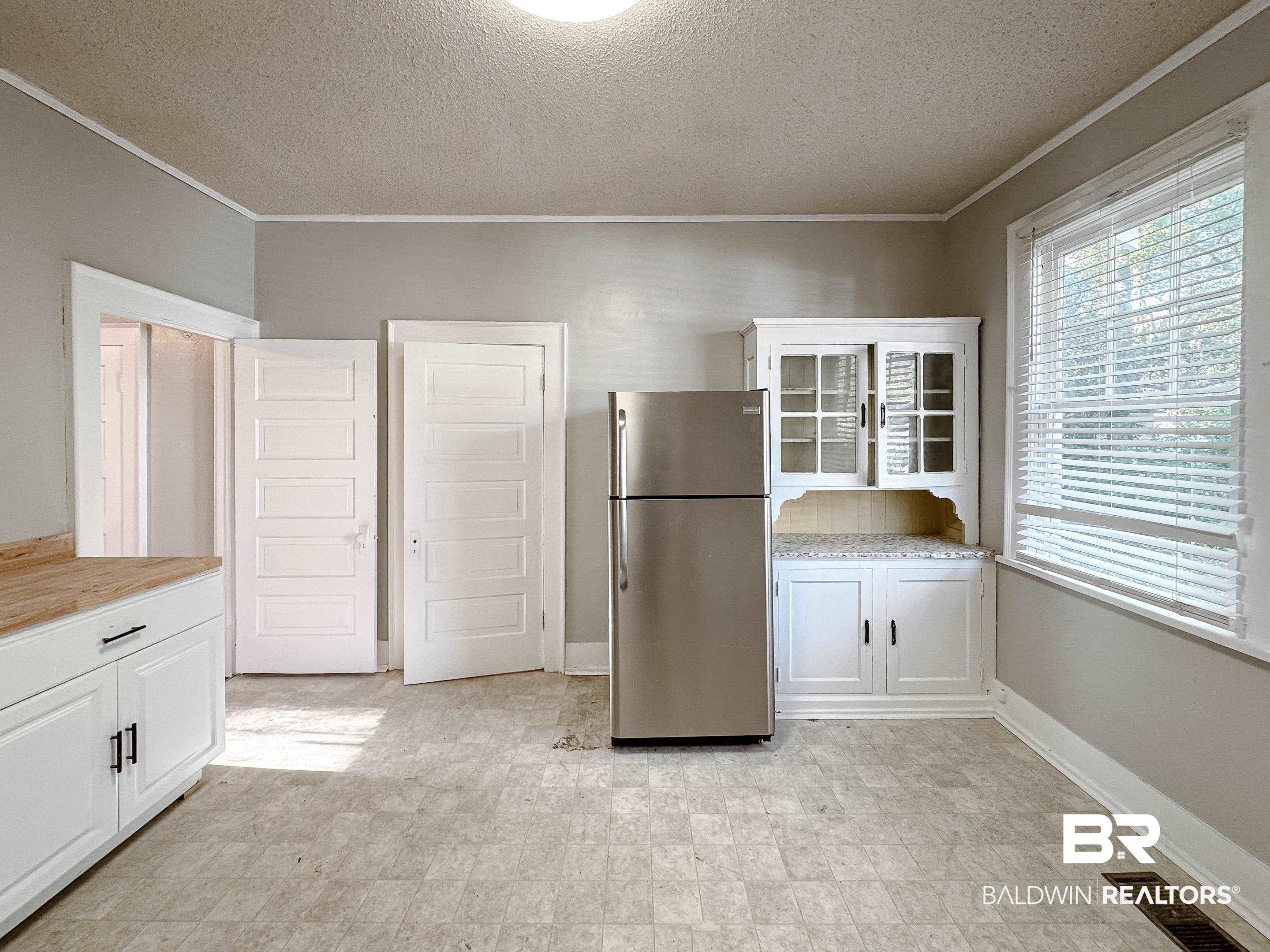 206 1st Street Mobile, AL 36611 - Photo 12 of 26 Kitchen with white cabinetry, freestanding refrigerator, a textured ceiling, crown molding, and butcher block countertops