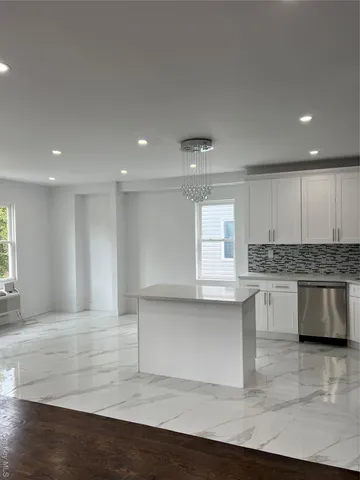 a large white kitchen with kitchen island a sink white cabinets and stainless steel appliances