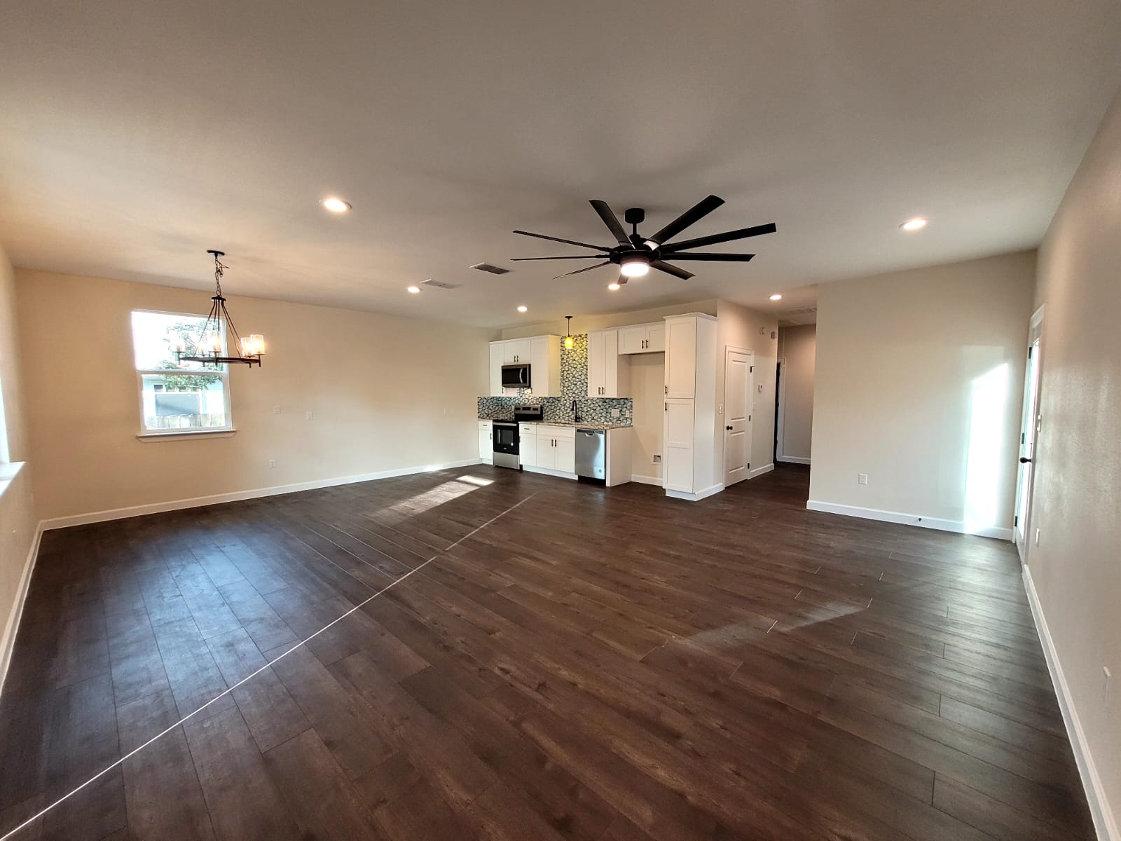 750 South Main Street Lockhart, TX 78644 - Photo 4 of 31 Unfurnished living room featuring ceiling fan, dark wood finished floors, and suspended lighting
